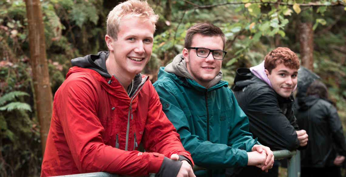 3 male students with forest backdrop