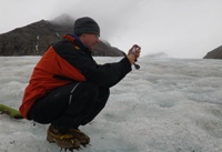 Dr Arwyn Edwards, darlithydd mewn Gwyddorau Biolegol yn IBERS, yn casglu samplau o facteria yn blodeuo ar Svalbard.