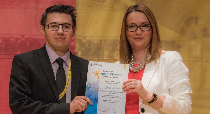 Jarrod Thomas being presented with his graduation certificate from the Aberystwyth Summer University by Kirsty Williams AM, Welsh Government Cabinet Secretary for Education, August 2017