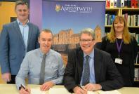 Chwith i'r dde: Dr Wyn Morris, Alun Jones, Yr Athro Tim Woods a Laura McSweeney yn arwyddo'r contract newydd