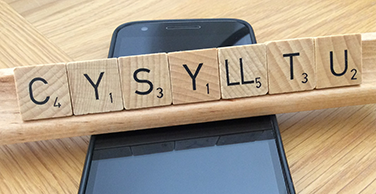 Ffôn symudol a'r gair 'cysylltu' ar deiliau Scrabble