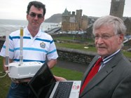 (Chwith i'r Dde) Hefin James o Adran Gwasanaethau Gwybodaeth Prifysgol Aberystwyth yn dal un o'r trosglwyddyddion WiFi a'r Cynghorydd Carl Williams, Aelod Cabinet Cyngor Sir Ceredigion sydd yn gyfrifol am faterion trawsbynciol.