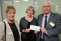 John Lewis (dde), mab Rhys Lewis, a Ms Brenda Dobney (chwith) yn cyflwyno siec o £10,000 i’r Athro April McMahon