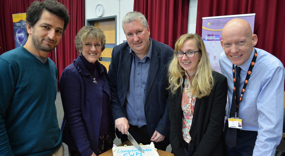 Chwith i’r Dde: Torri’r gacen; Dr Taulat Guma, Dr Lucy Taylor, yr Athro Michael Woods, Dr Elin Royles a Dr Rhodri Llwyd Morgan, Dirprwy Is-Ganghellor Prifysgol Aberystwyth yn nodi sefydlu Canolfan Gwleidyddiaeth a Chymdeithas Cymru.