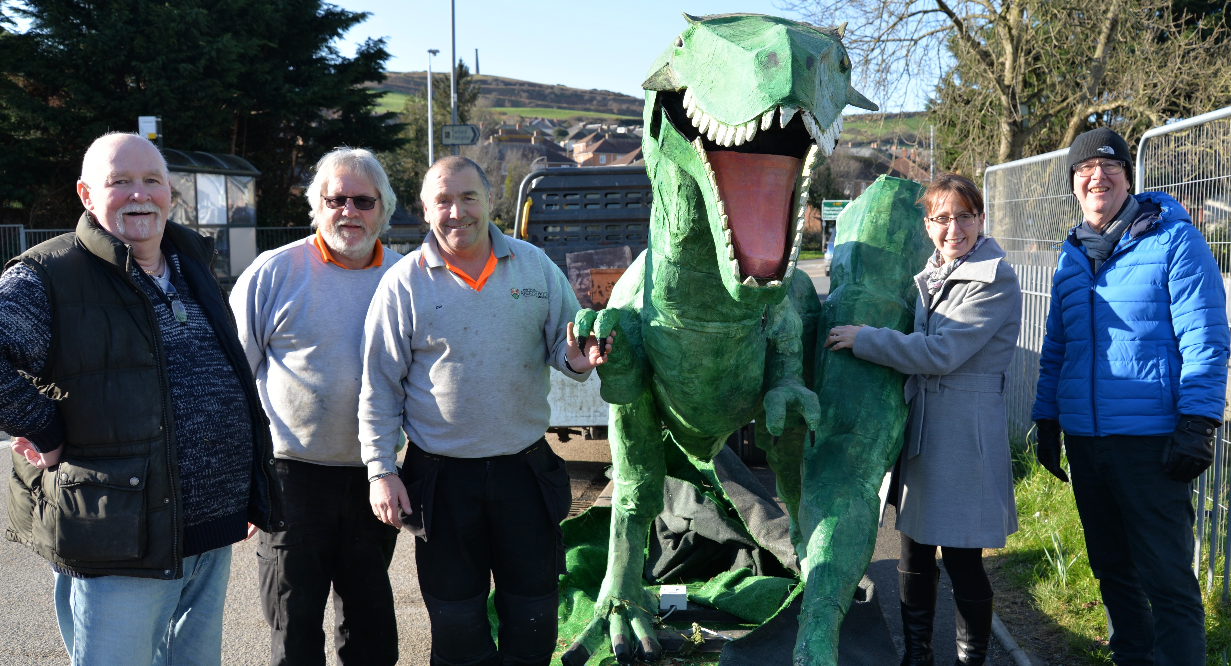 Dai y Deinosor ar ei ffordd o swyddfeydd Fformwm Gymunedol Penparcau i’r Hen Goleg yng nghwmni (chwith i’r dde) George Barratt, Fforwm Penparcau, Jeff Dowse a Dai Gornall o Dîm Eiddo Prifysgol Aberystwyth, Nia Davies, Prosiect Hen Goleg Prifysgol Aberystwyth a Bryn Jones, Fforwm Penparcau.