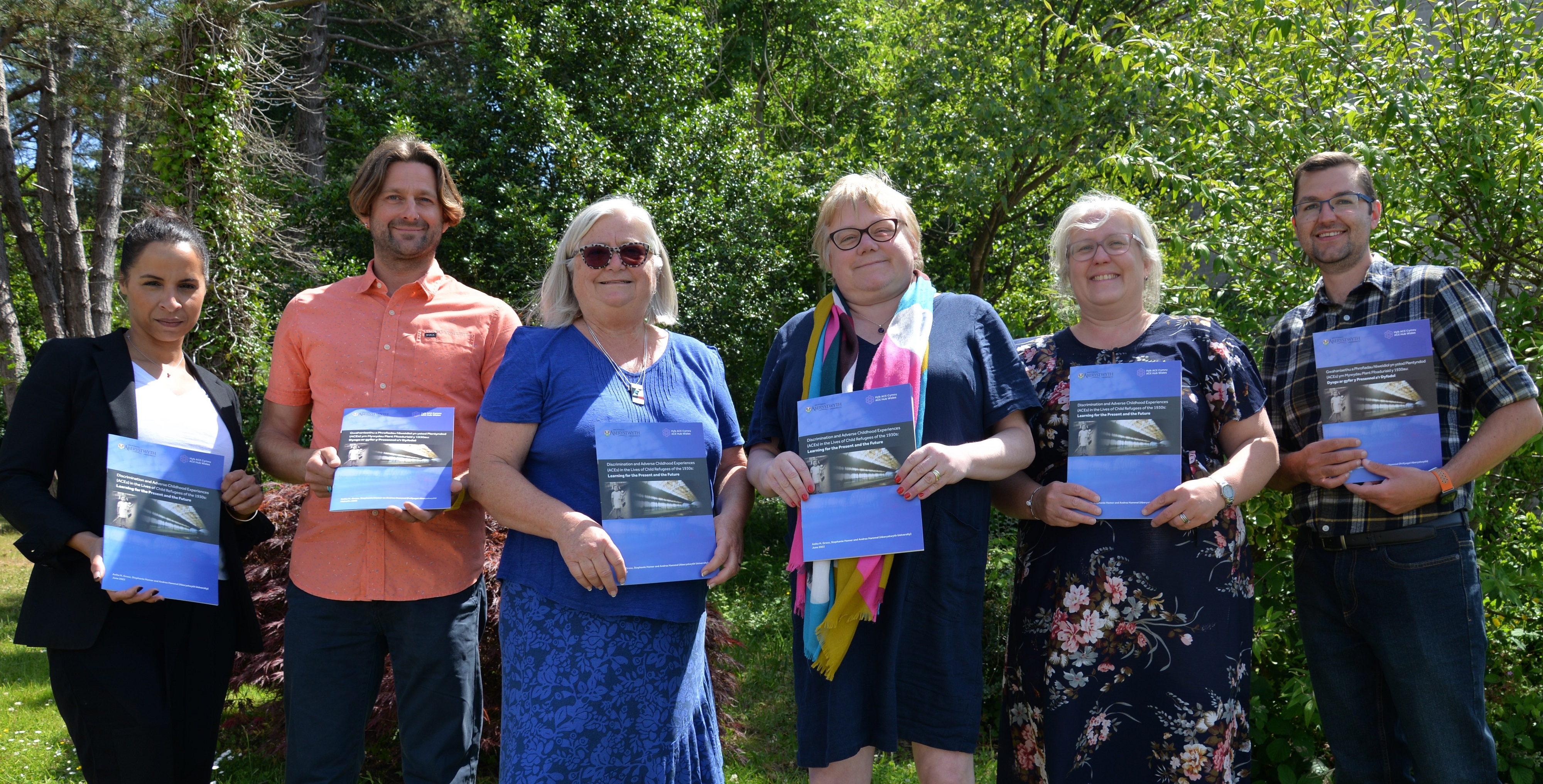 O’r chwith i’r dde, llun a dynnwyd yn lansiad yr adroddiad: Emma Wools, Dirprwy Gomisiynydd Heddlu a Throseddu De Cymru; Mark Jones, Cyfarwyddwr Higher Plain Research & Education; Anita H. Grosz, Prifysgol Aberystwyth; Dr Andrea Hammel, Prifysgol Aberystwyth; Joanne Hopkins, Cyfarwyddwr Rhaglen Profiadau Niweidiol yn ystod Plentyndod, Cyfiawnder Troseddol ac Atal Trais, Iechyd Cyhoeddus Cymru; a John Davies, Pennaeth Cynhwysiant a Chydlyniant, Llywodraeth Cymru