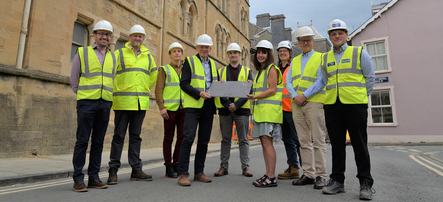 Aelodau Tîm Dylunio’r Hen Goleg yn nodi tynnu’r lechen gyntaf o do hen adeilad Ystadau’r Brifysgol, cyn i’r gwaith ddechrau i glirio’r safle ar gyfer yr atriwm newydd drawiadol a fydd yn fynedfa i’r adeilad rhestredig Gradd 1.