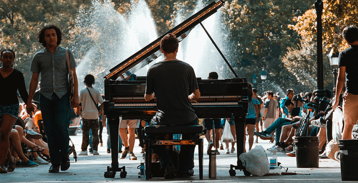 Golygfa o Central Park, Efrog Newydd - Person yn chwarae piano cyngerdd a phobl yn eistedd ar feinciau ac yn cerdded heibio