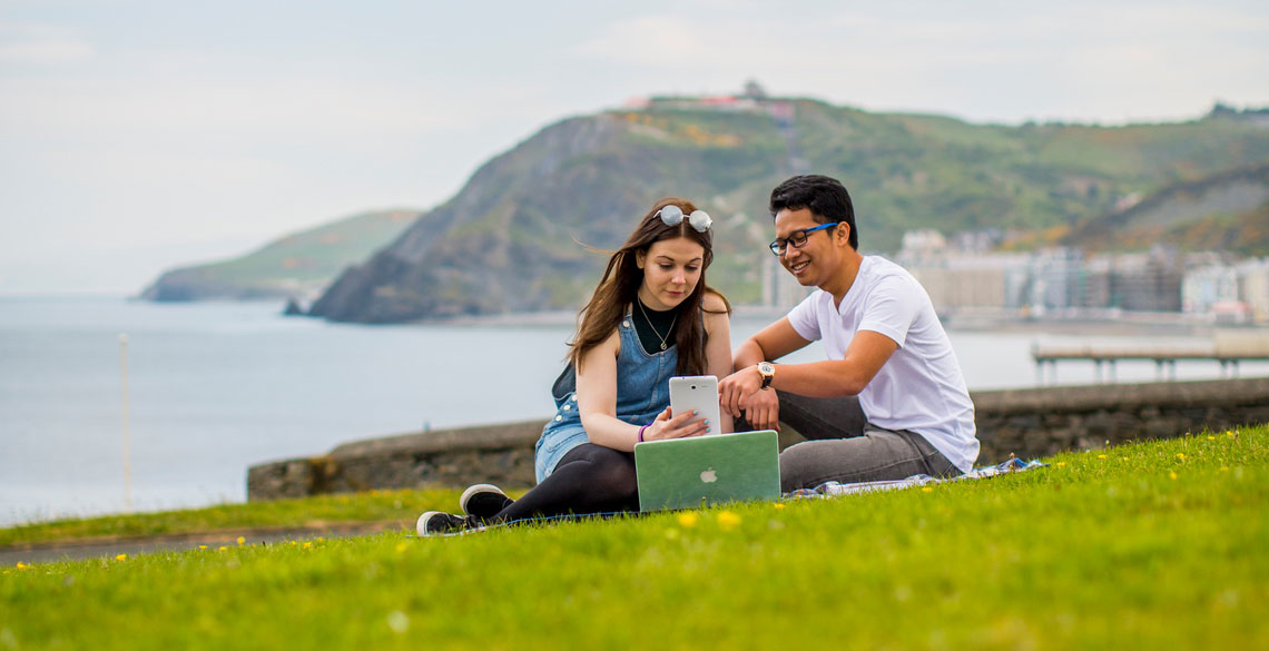 Students sitting on grass with a laptop