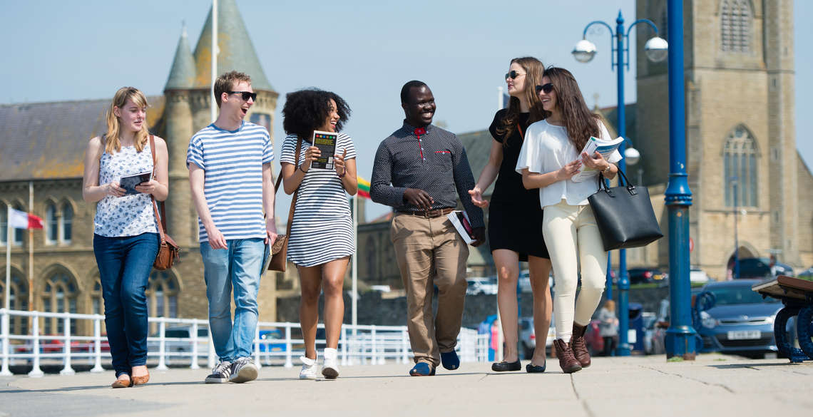 Students laughing and enjoying a walk along the promenade in Aberystwyth.