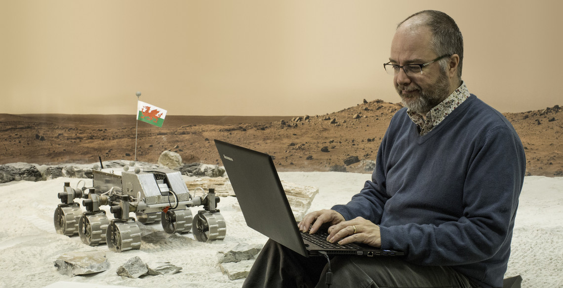 Man controlling a minature Mars rover robot