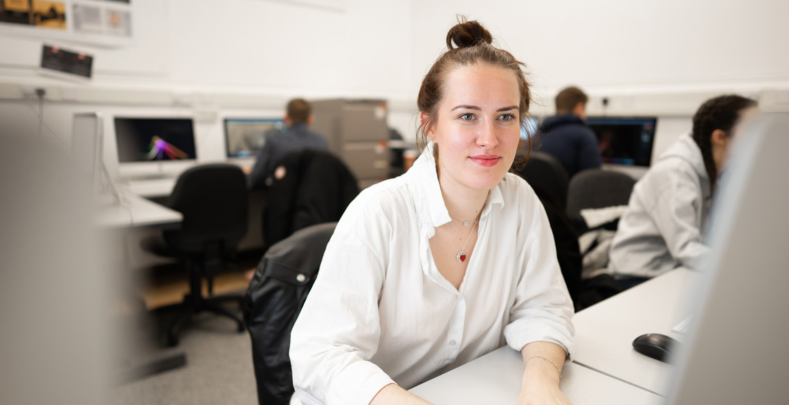 Female student sat at a desk looking at a computer