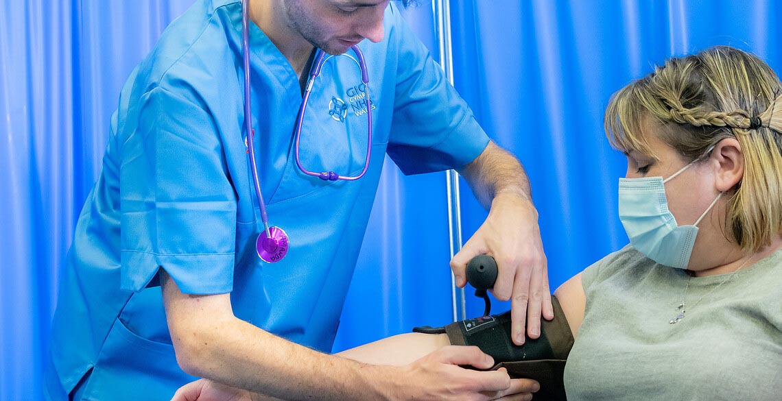 A male nurse taking a woman's blood pressure