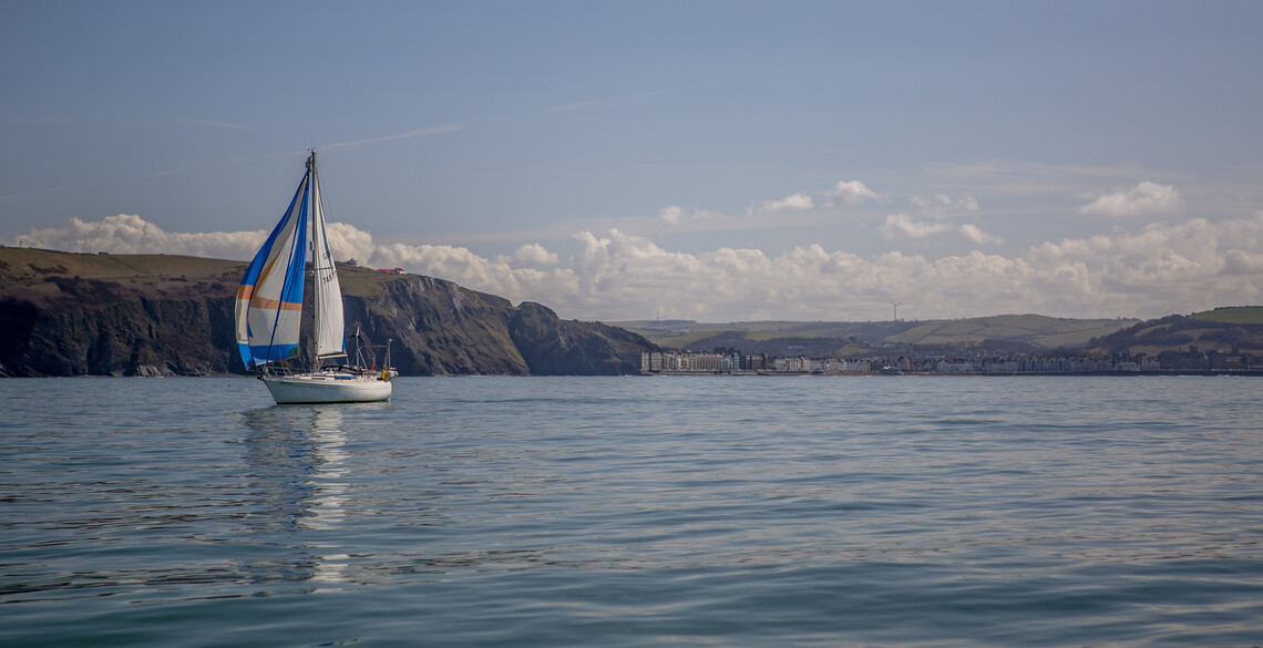 boat on sea with Aberystwyth town in the background.