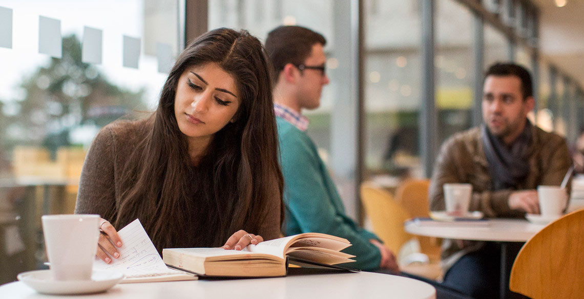 Student studying in the Arts Centre Cafe, Penglais Campus, Aberystwyth University. 