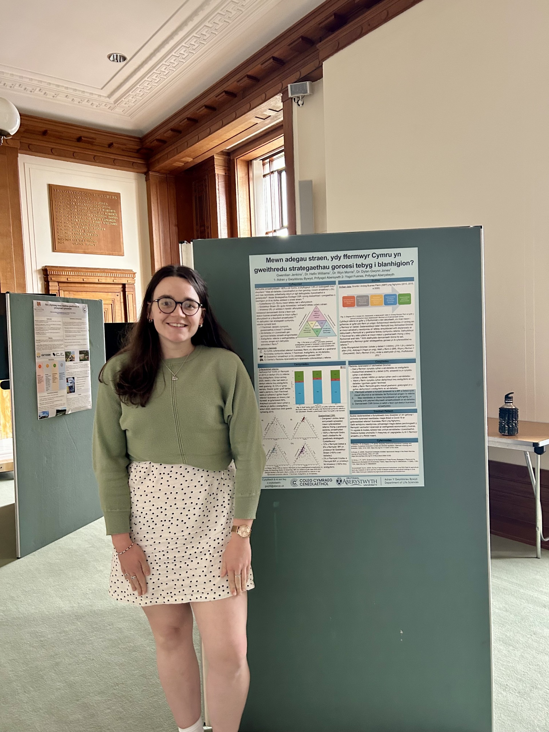 Gwenllian Jenkins presenting a poster of her research at the Coleg Cymraeg Cenedlaethol Conference in June 2025