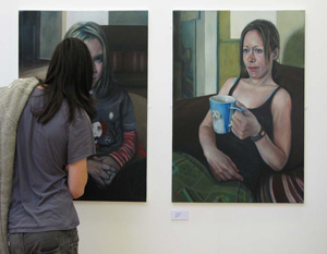 Student examining paintings on display.