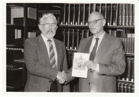 Dr. Bryan Rollason presenting a copy of Prof. Pierre Tucoo-Chala’s book, ‘Pau Ville Anglaise,’ to W. Dieneman (Librarian), 20 June 1986.