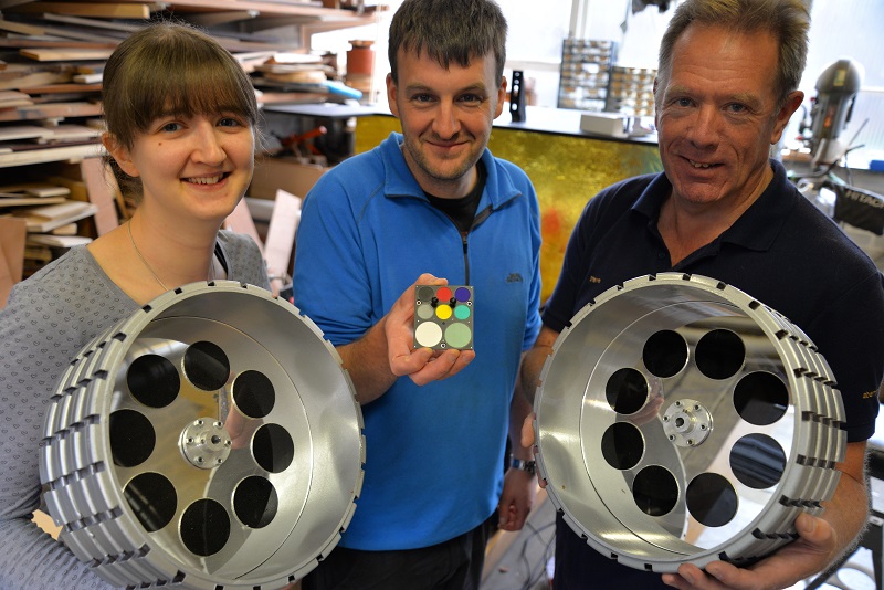 Wheels of steel: Dr Helen Miles and Stephen Fearn holding the wheels of the ExoMars Rover model and Dr Matt Gunn showing the mission’s colour swatch that has been inspired by medieval stained glass.