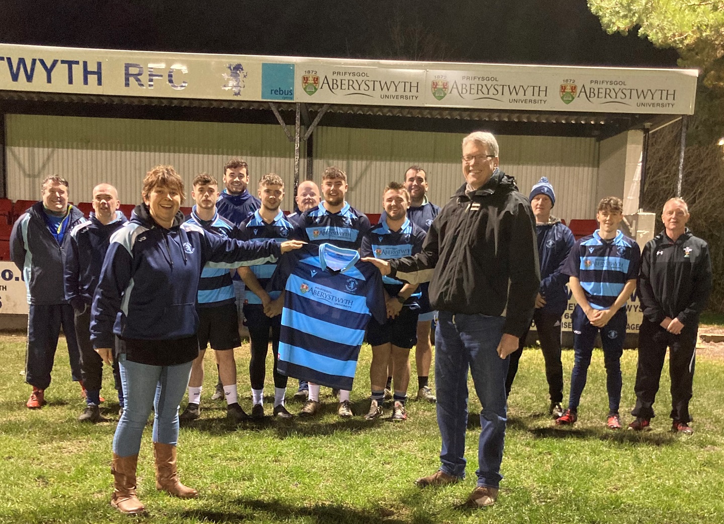 Pictured are Nerys Hywel, Club Chair receiving the new Aberystwyth RFC Athletic and Youth team shirts from Professor Tim Woods, Pro Vice-Chancellor for Learning, Teaching and Student Experience at Aberystwyth University, Coaches. Also pictured are players, including Club Captain Arwel Lloyd and Vice-Captain Matthew Hughes.