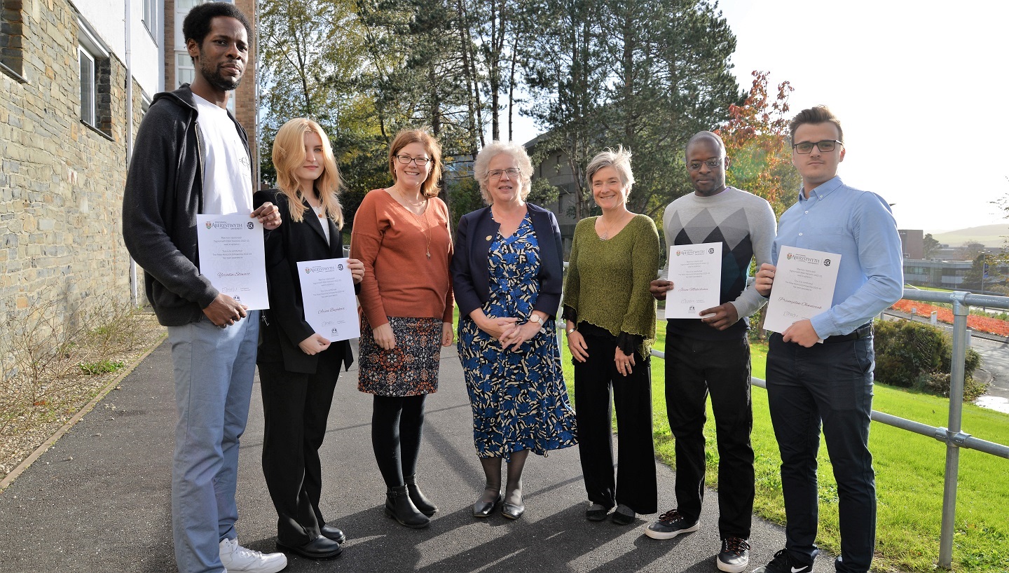 Presentation of 2022 Peter Hancock Scholars: Left to Right; Yerodin Stewart (Psychology); Arina Bugakova (Business and IT); Jennifer Pollard, representing Peter Hancock and Pat Pollard; Professor Elizabeth Treasure, Vice-Chancellor; Pat Pollard, representing Peter Hancock and Pat Pollard; Jason Makechemu (Astro Physics); and Przemyslaw Olewniczak (Genetics)..