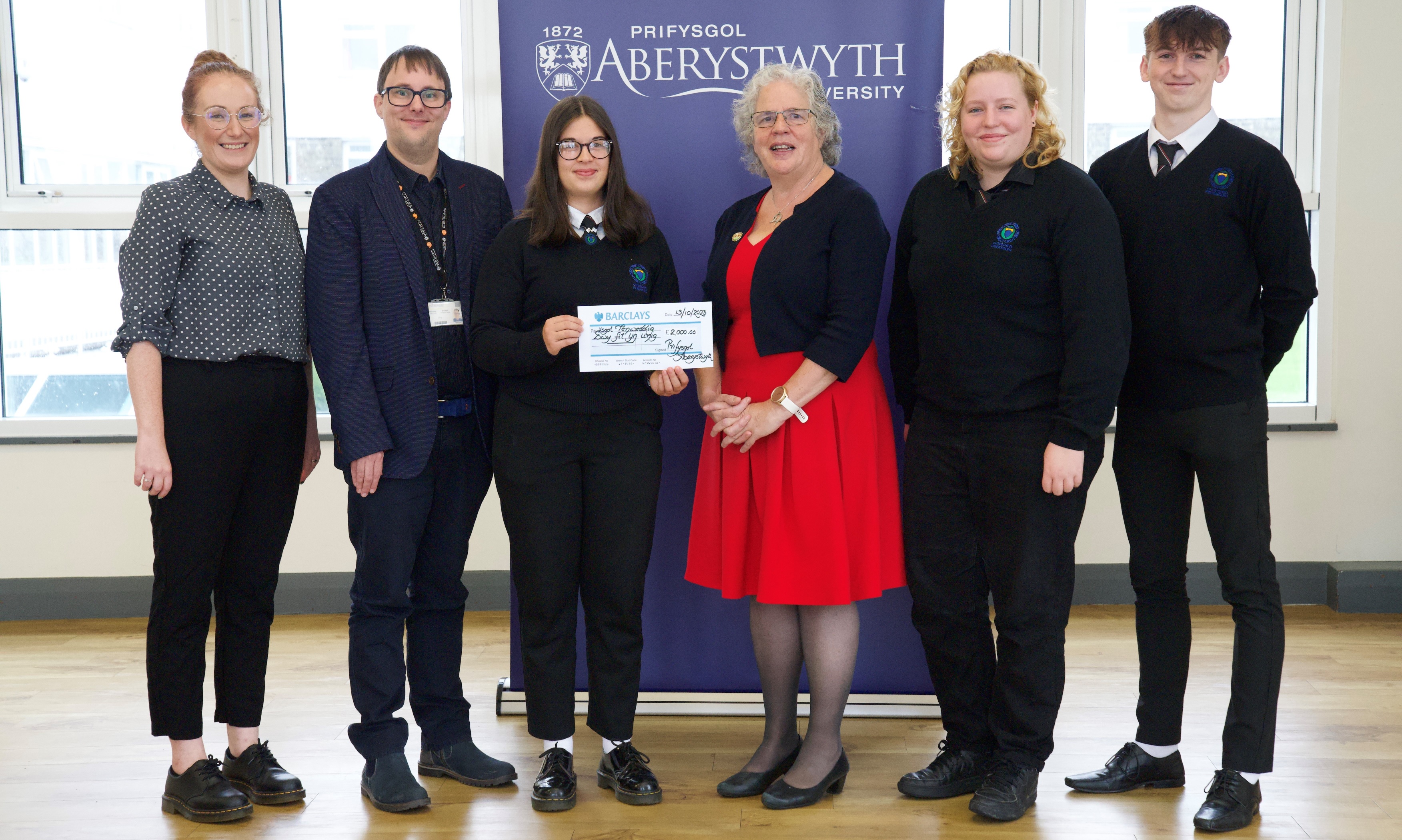 Members of the winning Penweddig team Maria Jones, Elain Tanat Morgan (second from the right) and Noa Rowlands presented with a cheque for £2000 by Professor Elizabeth Treasure, Vice-Chancellor of Aberystwyth University in the company of Jane Richards, Head of Business at Ysgol Penweddig (far left) and Mr Jonathan Fry from Aberystwyth Business School.