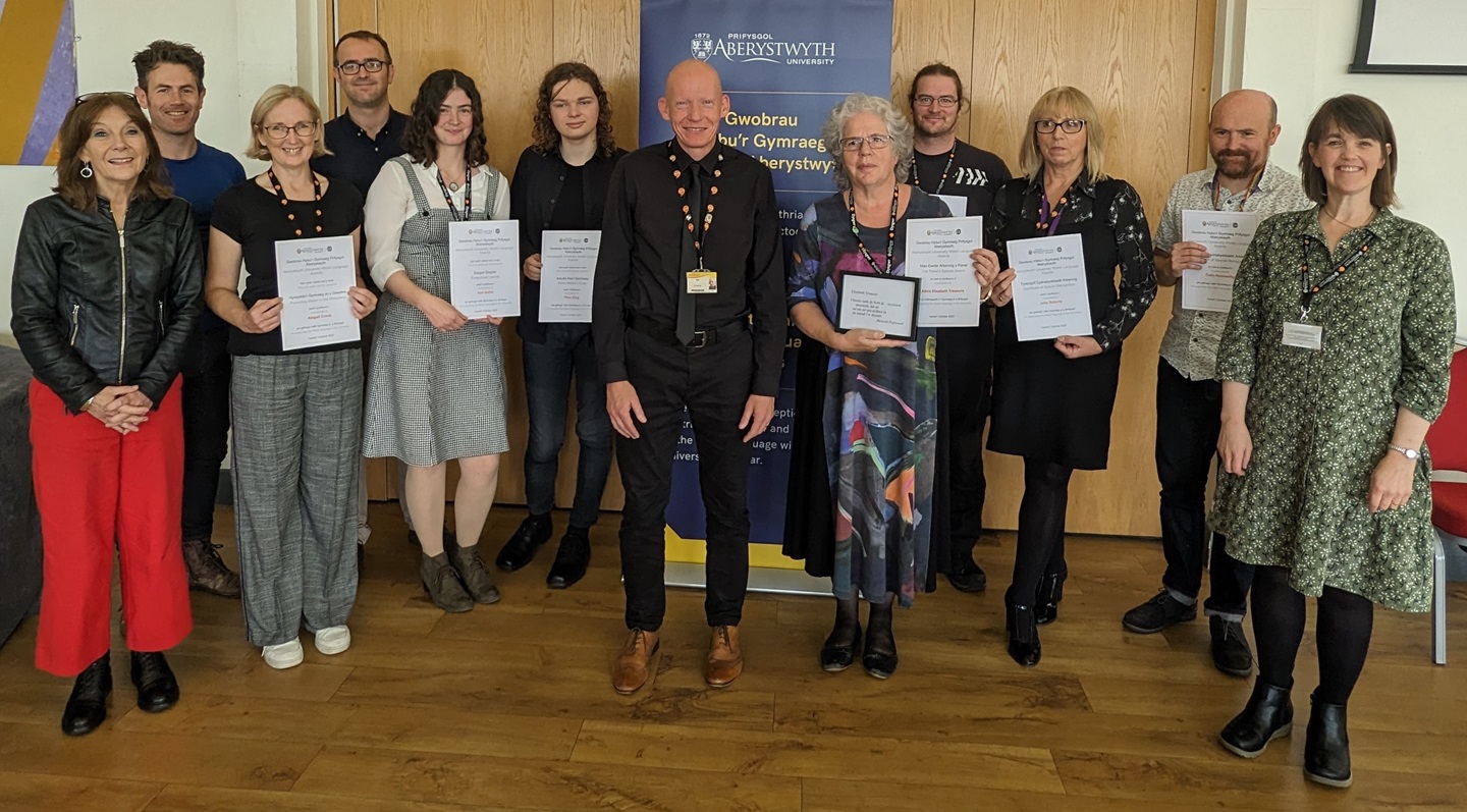 (From left to right) – Professor Mererid Hopwood, Dr Eurig Salisbury, Nia Ellis (on behalf of Abigail Crook), Dr Hywel Griffiths, Kate Barber, Ffion King, Dr Rhodri Llwyd Morgan, Professor Elizabeth Treasure, Chris Stewart, Julie Roberts, Colin Nosworthy and Lowri Jones.