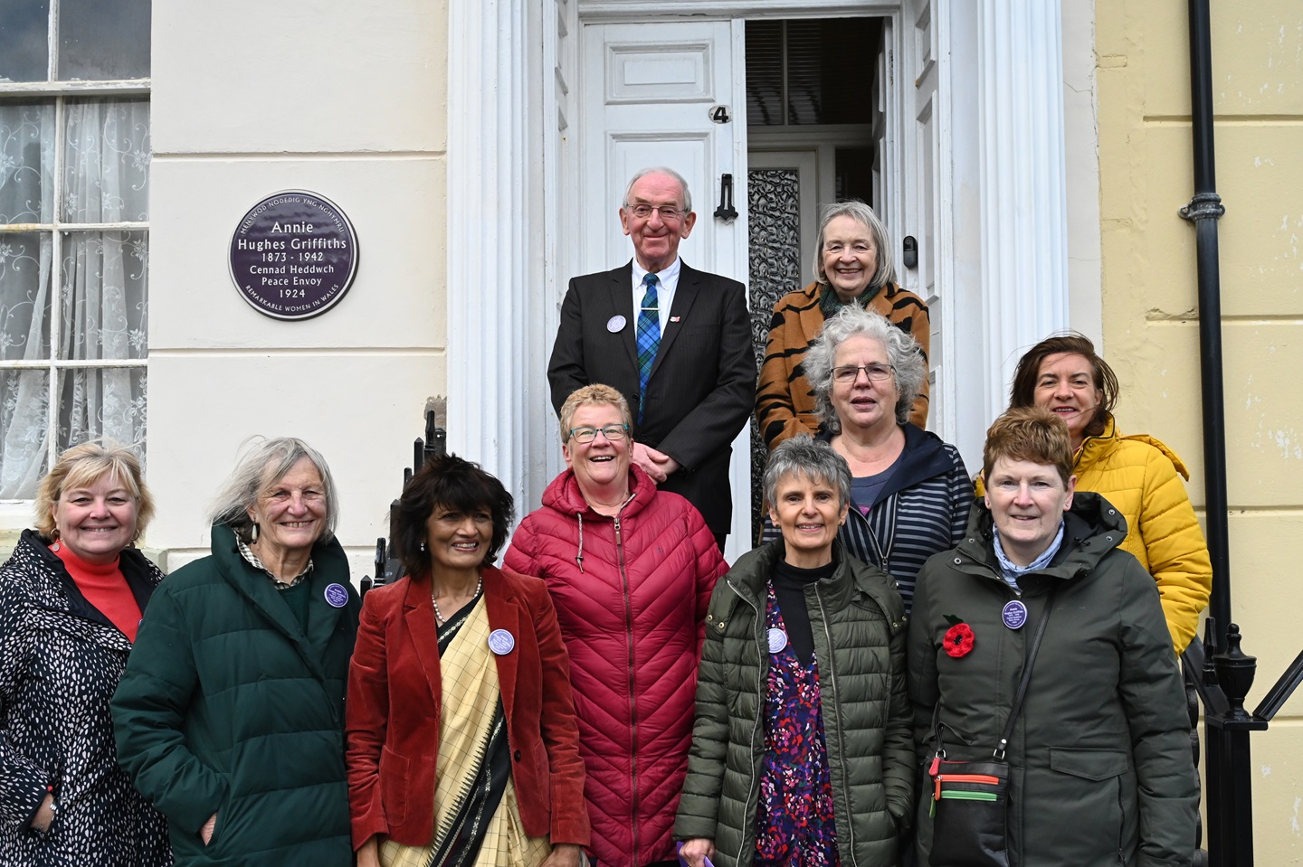 Plaque unveiling with guests including Rolant Elis (grandson), Meg Elis (granddaughter), Vice-Chancellor of Aberystwyth University Professor Elizabeth Treasure, Eluned Morgan MS, and members of the Welsh Purple Plaques Committee.