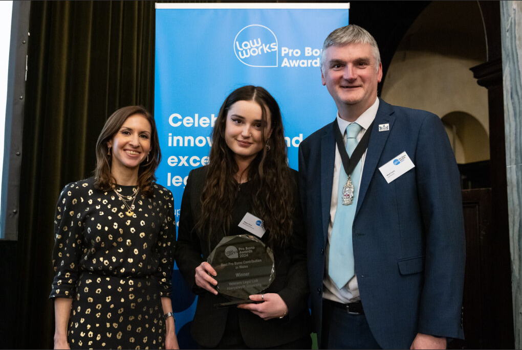 Veterans Legal Link case worker Megan Perrins (centre) accepting the award on behalf of the team at the award ceremony in London on 4 December 2024, with event host and political commentator Tamara Cohen and Vice President of the Law Society of England and Wales, Mark Evans.