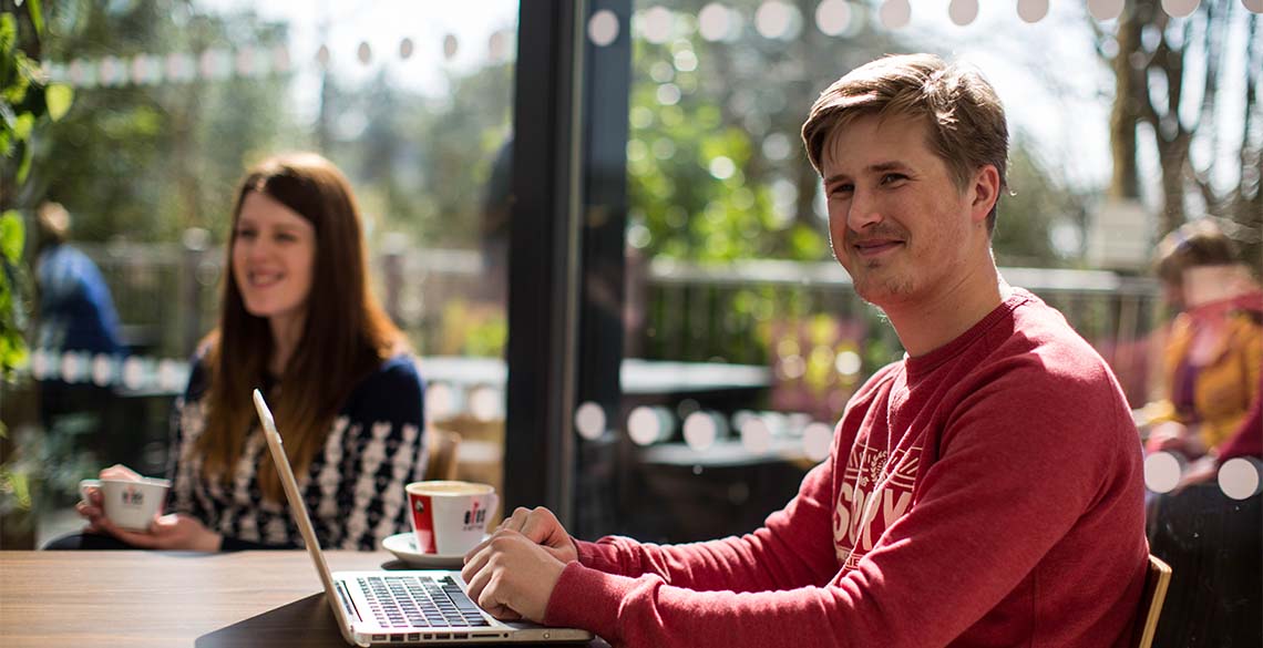 Students smiling; student working on a laptop