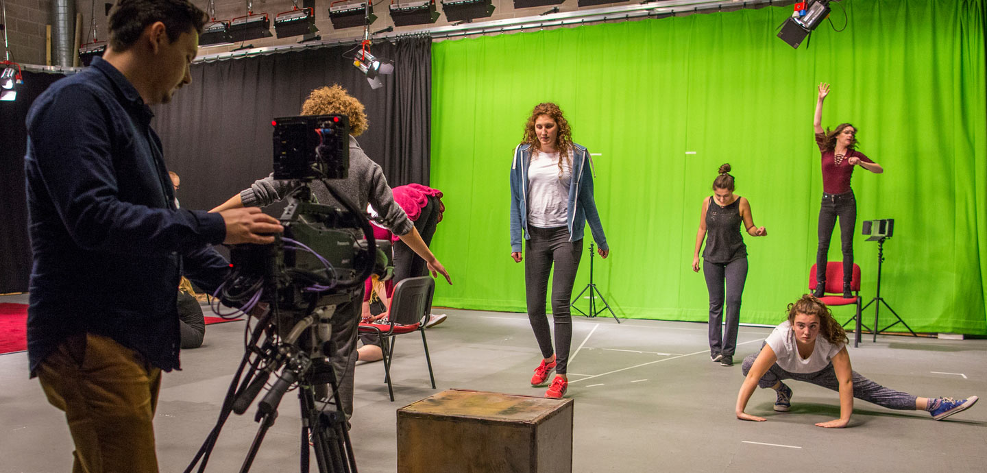 A group of students filming performers on stage