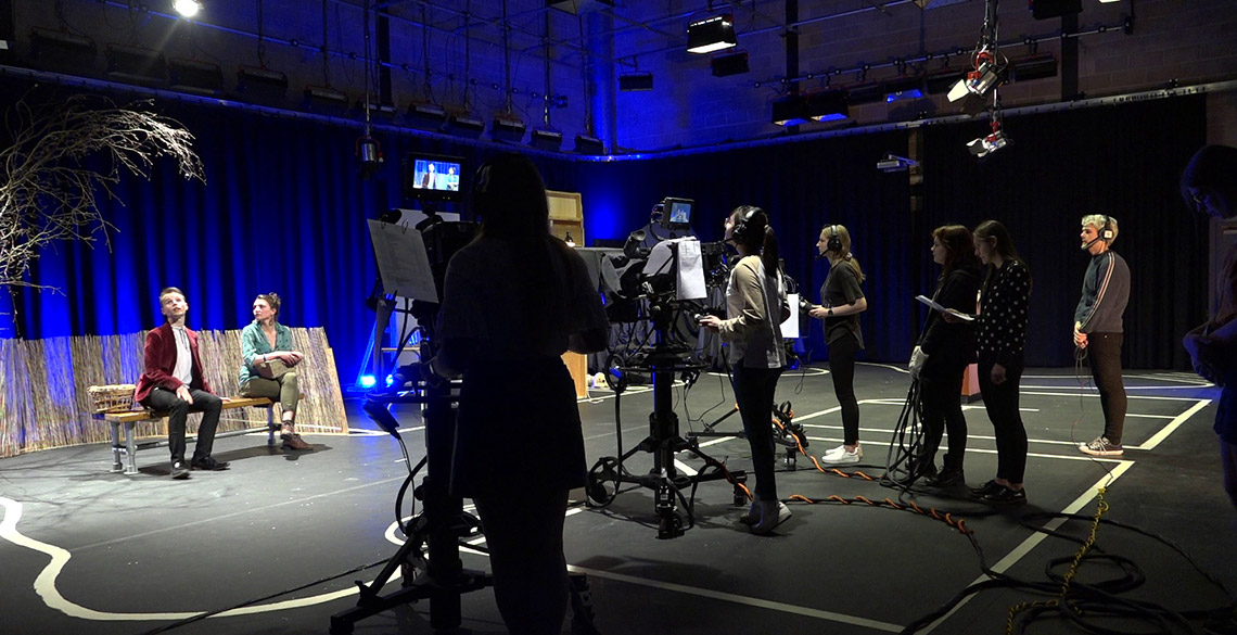 A group of students filming performers on stage