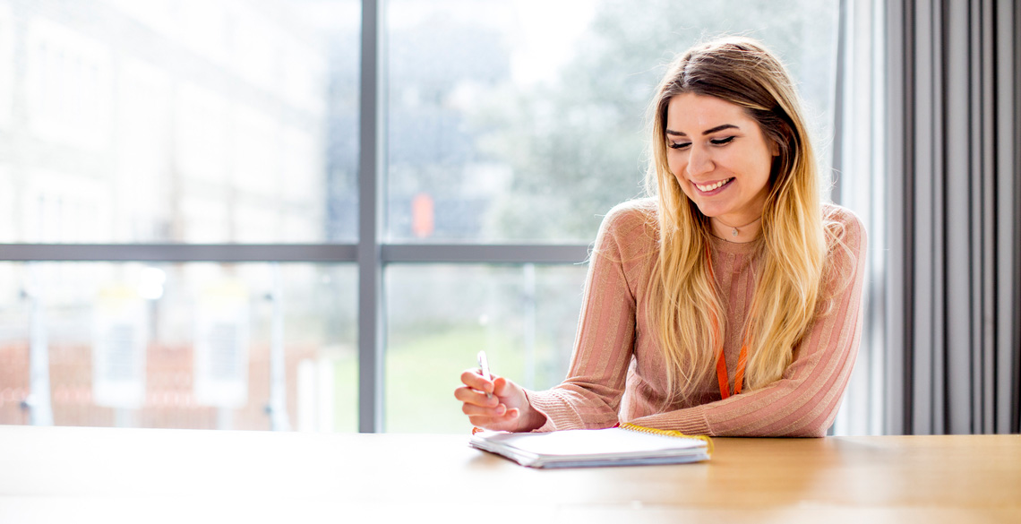 Smiling student sitting at a table with a notebook
