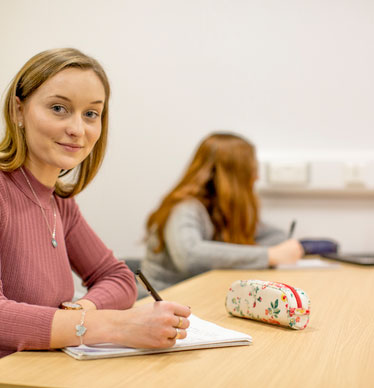 Photo of a student sat at a desk, writing